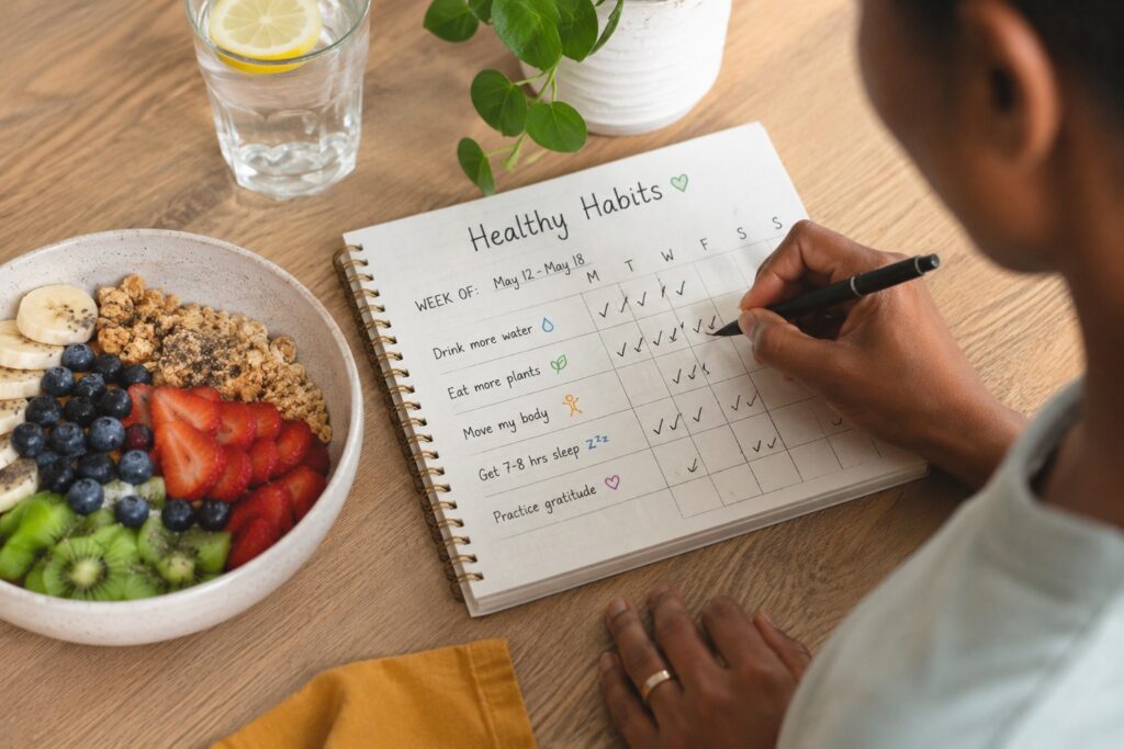 Person checking off healthy habits on a weekly planner beside a fresh plant-based breakfast bowl, promoting simple and sustainable healthy eating.